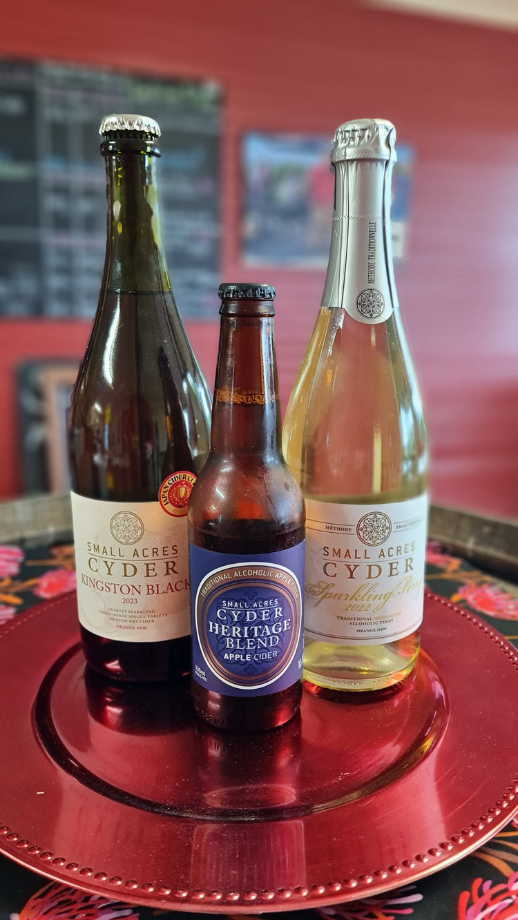 Bottles of cider arranged on a plate: Knigston Black, Heritage Blend and Sparkling Perry