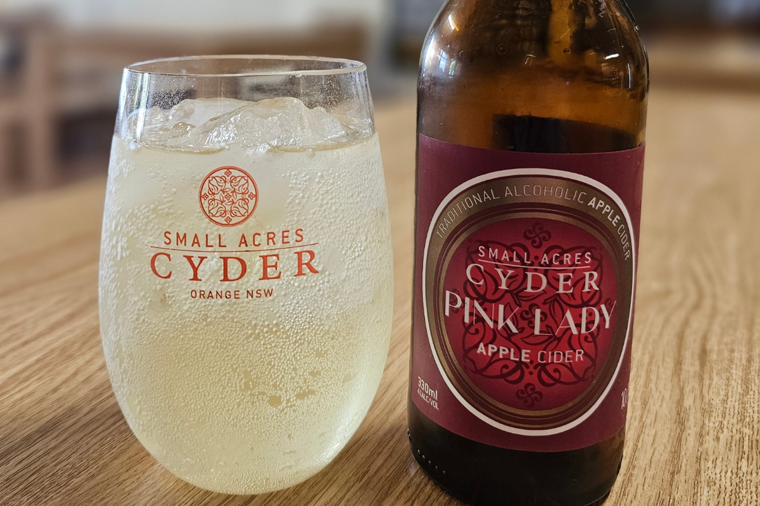 A bottle of Pink Lady and a glass of cider with ice in it