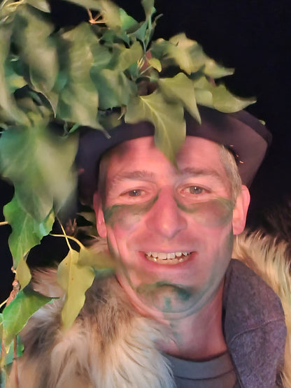 A man wearing a hat with Ivy on it and green makeup on his face.