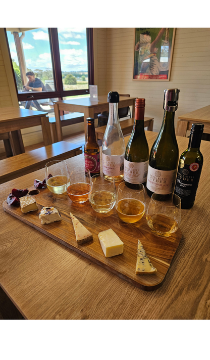 A selection of cheese and matching ciders on a table in a brightly lit cellar door.
